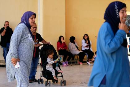 Personas desplazadas del sur de Líbano caminan por una escuela utilizada como refugio en la ciudad portuaria de Tiro, Líbano, viernes 20 de octubre de 2023. 