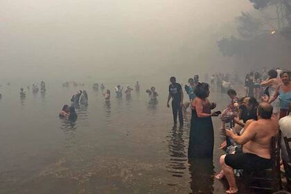 Personas en la playa cubiertas por el humo producto de los incendios forestales que castigan a Grecia