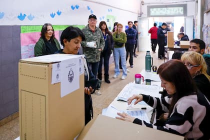 Personas esperan en una mesa de votación este domingo, durante la jornada de elecciones legislativas, en un colegio de Lanús
