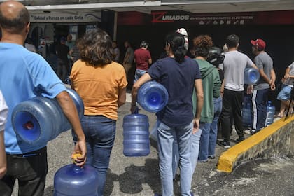 Personas hacen fila para llenar bidones con agua en La Carlota, un día después de la captura de Nicolás Maduro por fuerzas estadounidenses, el 4 de enero de 2026, en Caracas, Venezuela
