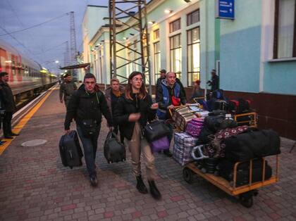 Personas llegadas desde Kherson llevan sus pertenencias a lo largo de un andén para su posterior evacuación a las profundidades de Rusia en la estación de tren de Dzhankoi en Crimea el 21 de octubre de 2022.