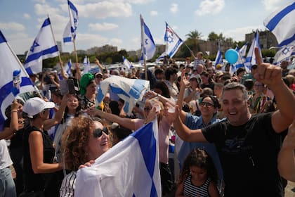 Personas ondean banderas israelíes en señal de celebración mientras esperan afuera del hospital Beilinson en Petah Tikva, Israel, el lunes 13 de octubre de 2025