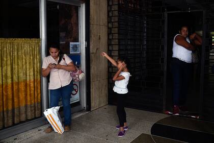 Personas permanecen afuera de un restaurante durante el corte de energía.