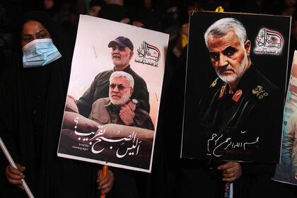 Personas portan retratos del difunto comandante iraquí Abu Mahdi al-Muhandis y del comandante iraní Qasem Soleimani en el aeropuerto de Bagdad, el 2 de enero de 2021, en el lugar de su asesinato