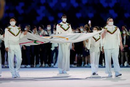 Personas presentan la bandera olímpica durante la ceremonia de apertura en el Estadio Olímpico de los Juegos Olímpicos de Verano de 2020, el viernes 23 de julio de 2021, en Tokio, Japón.