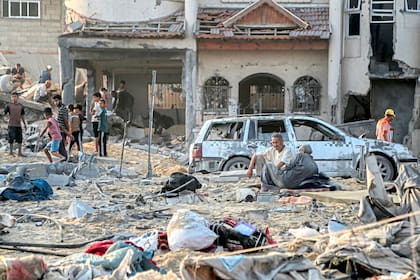 Personas sentadas junto a un edificio destruido tras el bombardeo israelí nocturno en el barrio japonés al noroeste de Khan Yunis, en el sur de la Franja de Gaza, el 28 de julio de 2025