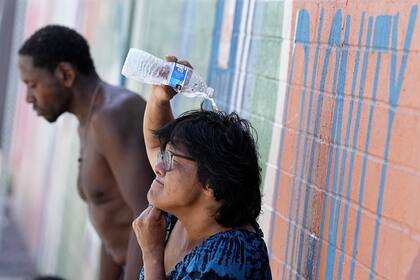 Personas sin hogar intentan refrescarse con agua fría fuera del Justa Center, un centro diurno para personas sin hogar de 55 años o más, el 14 de julio de 2023 en el centro de Phoenix.