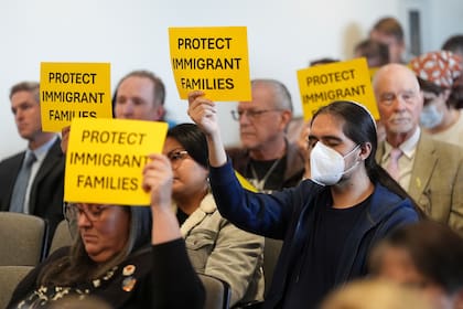 Personas sostienen letreros en los que exigen protecciones a las familias inmigrantes durante una reunión de la junta de supervisores del condado de San Diego, el martes 10 de diciembre de 2024, en San Diego. (AP Foto/Gregory Bull)