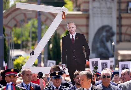 Personas sostienen una imagen del presidente ruso Vladimir Putin y una letra Z, durante la ceremonia del Día de la Victoria en Belgrado, Serbia, el lunes 9 de mayo de 2022.