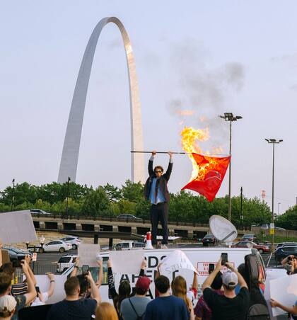 Peter McIndoe quema una bandera Cardinals en Saint Louis, durante una protesta satírica (Madeline Houston via The New York Times)