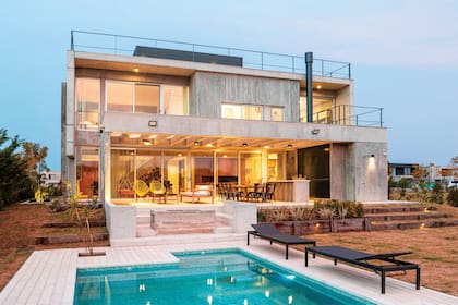 Pileta con revestimiento de venecitas y deck cementicio (Pavimenti). Dúo de reposeras ‘Annet’ en ratán (Fontenla).