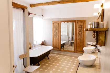 Piso de calcáreos y una bañadera restaurada que llegó desde Tucumán. Las vigas dialogan con el roble de los espejos, recuerdo de los roperos que había en su casa familiar.