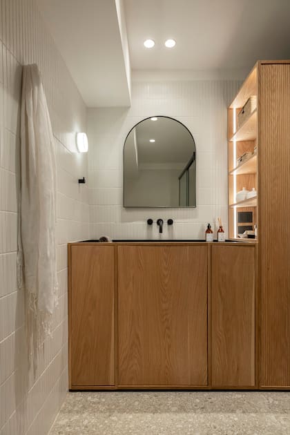 Piso de porcelanato 'Pietra Gris' de Sant'Agostino (SBG), cerámicas (Fika), mesada y bacha conformada de granito 'Negro Brasil' terminación leather, espejo con marco metálico negro (Alejandra Nusenovich).