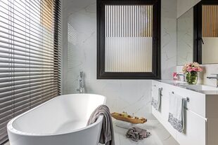 Piso y paredes de porcelanato ‘Bianco Apuano’ (Vite). Mueble con mesada de Corian. Toallas de algodón, sales de baño, jabón y cepillo (Claudia Adorno). Cortinas de tablas de PVC (Alix Ruiz Duggan).