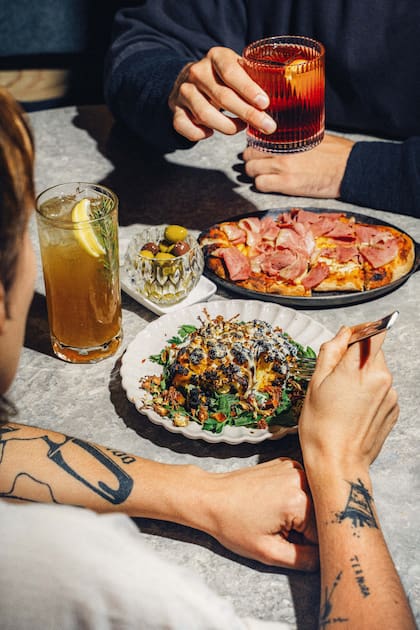 Pizza de masa madre con stracciatella y mortadella con pistachos; coliflor al carbón con tahini, limón y dátiles