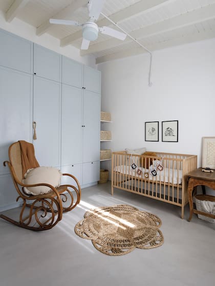 Placard (Estudio Cántaro Bardó) de MDF pintado de celeste. Alfombra (Philippa Deco Boutique), mecedora (Michael Thonet) de los abuelos de María Eugenia. Cuna (Ikea), autito de madera (Lola y Chango). En los estantes, canastos de fibras naturales (Paysana). Obra en paper cut (Colores en Papel).