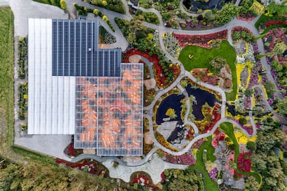Plano con vista superior del invernadero, con sus paneles solares y el paisaje con todos los colores del arco iris.
