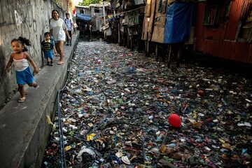 Las personas caminan a lo largo de un canal contaminado con plástico y basura en el Estero de San Lázaro en Manila.