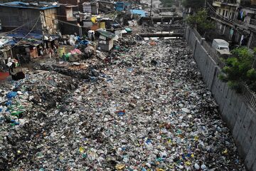 Canal de drenaje de aguas residuales contaminado cubierto de basura en un vecindario de bajos ingresos en Nueva Delhi.