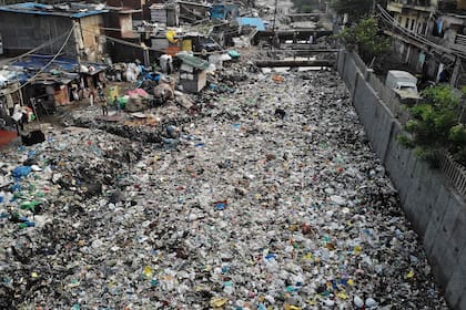 Canal de drenaje de aguas residuales contaminado cubierto de basura en un vecindario de bajos ingresos en Nueva Delhi.