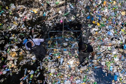 Trabajadores recolectan basura, incluidos desechos plásticos, en el río Matías Hernández en Costa del Este, Ciudad de Panamá.