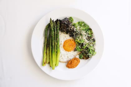 Plato de kale, espárragos, huevo y romesco.