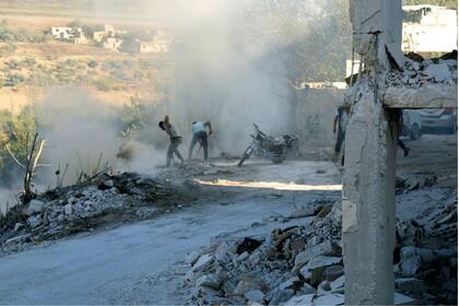 Pobladores intentan apagar el fuego en el lugar de un bombardeo