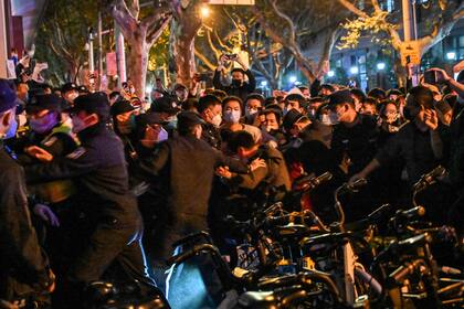 Police and guards arrest a man during some clashes in Shanghai on November 27, 2022, where protests against China's zero-Covid policy took place the night before following a deadly fire in Urumqi, the capital of the Xinjiang region. (Photo by HECTOR RETAMAL / AFP)