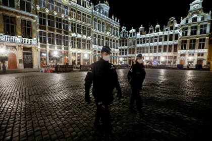 Policías con máscaras protectoras patrullan al inicio del toque de queda en Bruselas el 19 de octubre de 2020 como medida contra la propagación de la pandemia de coronavirus