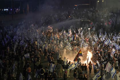 Policías de Israel usan cañones de agua para dispersar a manifestantes que bloquean una autopista durante una protesta contra los planes del gobierno del primer ministro Benjamin Netanyahu de reformar el sistema judicial, el miércoles 5 de julio de 2023, en Tel Aviv. (AP Foto/Oded Balilty)