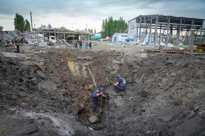 Policías inspeccionan un cráter causado por un proyectil ruso en Pokrovsk, en la región de Donetsk, en Ucrania, el 15 de junio de 2022. (AP Foto/Efrem Lukatsky)