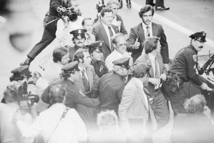 Policías y hombres de seguridad se llevan detenida a Sara Jane Moore, cuyos pies se pueden ver a la izquierda y al centro de la imagen