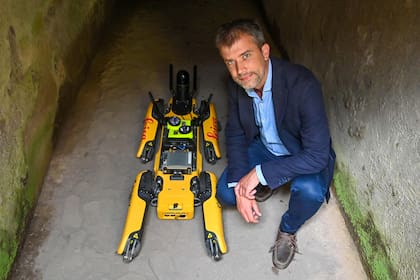 El director del sitio de Pompeya, Gabriel Zuchtriegel, posa con "Spot", un robot cuadrúpedo desarrollado por Boston Robotics, durante su presentación a los medios el 9 de junio de 2022 en el Parque Arqueológico de Pompeya, cerca de Nápoles.