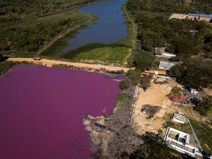 Un camino divide la laguna Cerro, el agua tiene un llamativo color púrpura en la zona que rodea a la curtiduría Waltrading, en Limpio, Paraguay