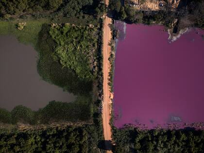 Un camino divide la laguna Cerro, el agua tiene un llamativo color púrpura en la zona que rodea a la curtiduría Waltrading, en Limpio, Paraguay