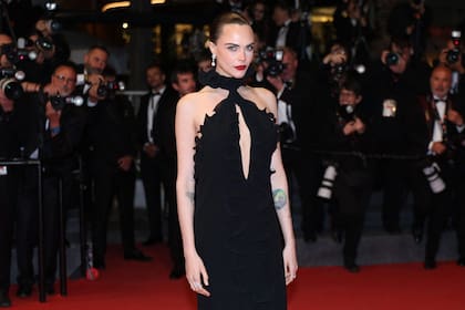 Por la noche, Delevingne optó por un vestido negro de silueta recta y caída fluida, con un pronunciado escote halter con profunda abertura central y volados escultóricos en el frente