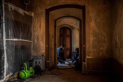 Los técnicos de restauración trabajan en un piso de baldosas en el Palacio, preparandose así para la reapertura luego de varios meses de confinamiento
