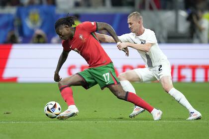 Portugal's Rafael Leao, left, challenges for the ball with Slovenia's Zan Karnicnik during a round of sixteen match between Portugal and Slovenia at the Euro 2024 soccer tournament in Frankfurt, Germany, Monday, July 1, 2024. (AP Photo/Ebrahim Noroozi)
