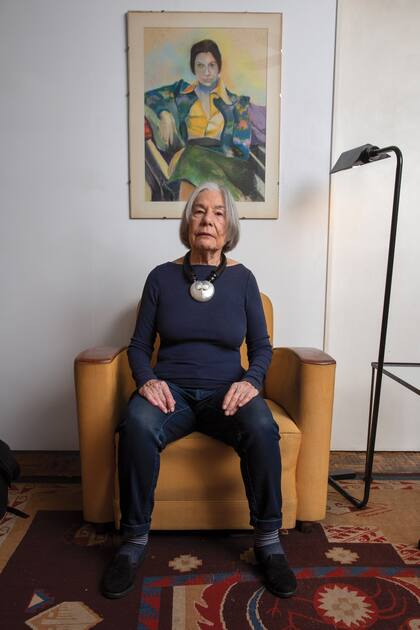 Posa sentada, de espaldas a un retrato suyo pintado por Ángel Pini. 