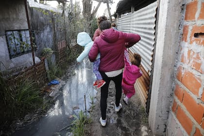 PRECARIEDAD. La falta de infraestructura básica que padece la provincia de Buenos Aires se refleja en la multiplicación de villas; en la imagen, una familia avanza por los pasillos de Villa Azul, en Quilmes