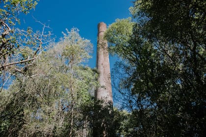 Como vestigio de lo que supo ser un proyecto industrial que duró muy poco, se erige una espectacular chimenea que sale del medio del monte