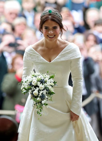 Radiante, sin velo y rompiendo tradiciones, Eugenia llevó un vestido de doble escote en "V" y falda abullonada, de Peter Pilotto. Sobre la falda, en brocado, la rosa de York, un guiño a la Reina; el trébol de Irlanda, origen de la familia Ferguson, y la hiedra, signo de su casa. 