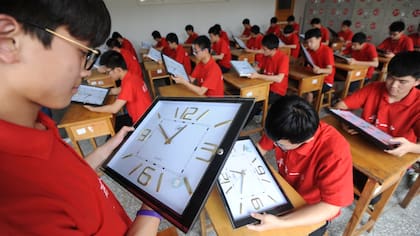 Profesores calibran los relojes de las aulas donde los alumnos rendirán los exámenes