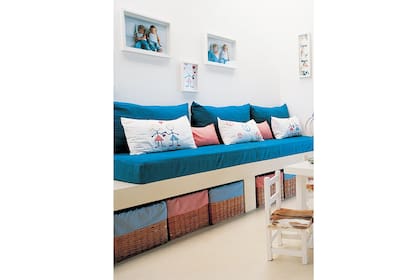 Una cama de obra a la que se le suman asientos de una placa completa para usar como colchón y, de paso, espacios de guardado con canastos