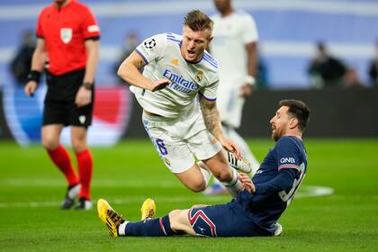 PSG's Lionel Messi tackles Real Madrid's Toni Kroos, falling, during the Champions League, round of 16, second leg soccer match between Real Madrid and Paris Saint-Germain at the Santiago Bernabeu stadium in Madrid, Spain, Wednesday, March 9, 2022. (AP Photo/Manu Fernandez)