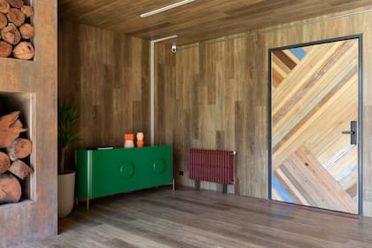 Puerta artesanal hecha con contramarcos reutilizados (Carpintería Martín Moreno). El viejo radiador cobró otra estética pintado de bordó.