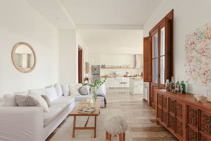 Puertas de demolición (El Depo). Espejo (Hydra Home). Sofá (Diamante Sillones) con funda (Deco con Alma). Mesa baja (El Garage). Alfombra tejida a mano, manta de lana y banco matero (Elementos Argentinos). Aparador heredado y restaurado (Dolita). Obra abstracta (Valeria Caligari). Pisos de porcelanato símil madera (Portinari).