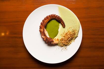Pulpo asado con crema de palta, salsa de espinaca y papas crocantes.