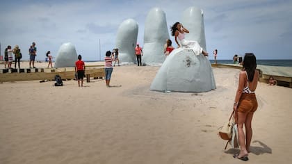 La gente se turna para sacarse fotos en "Los dedos", al inicio de La Brava