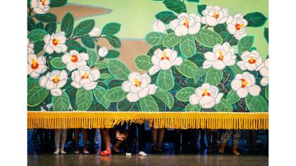 Un estudiante de Corea del Norte en el Palacio de los Niños Mangyongdae saluda desde abajo de la cortina después de una actuación